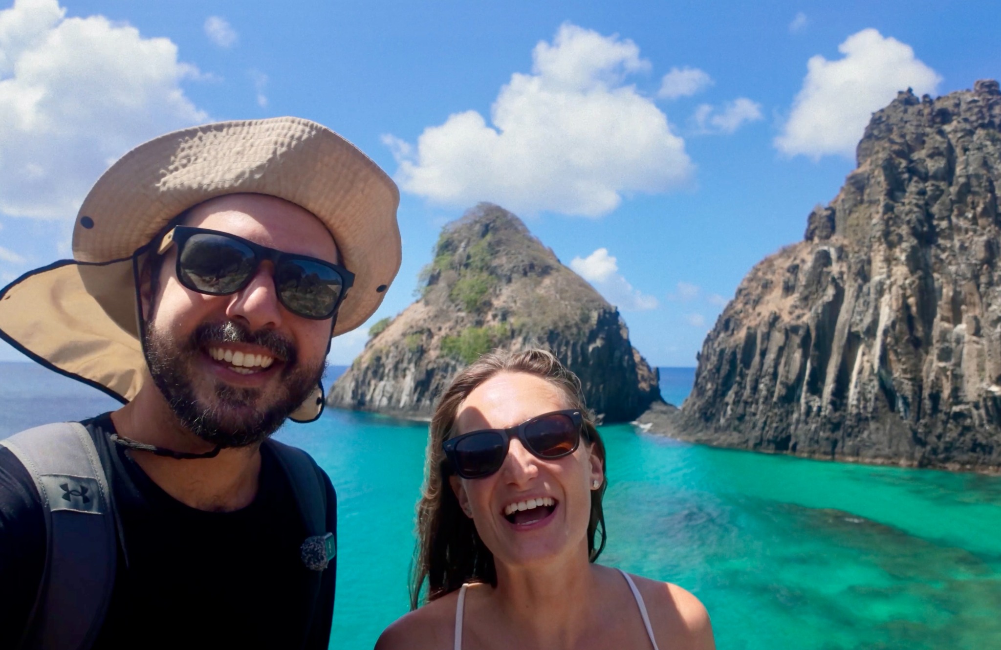 Daniel e Giovanna com o mar e formações rochosas ao fundo