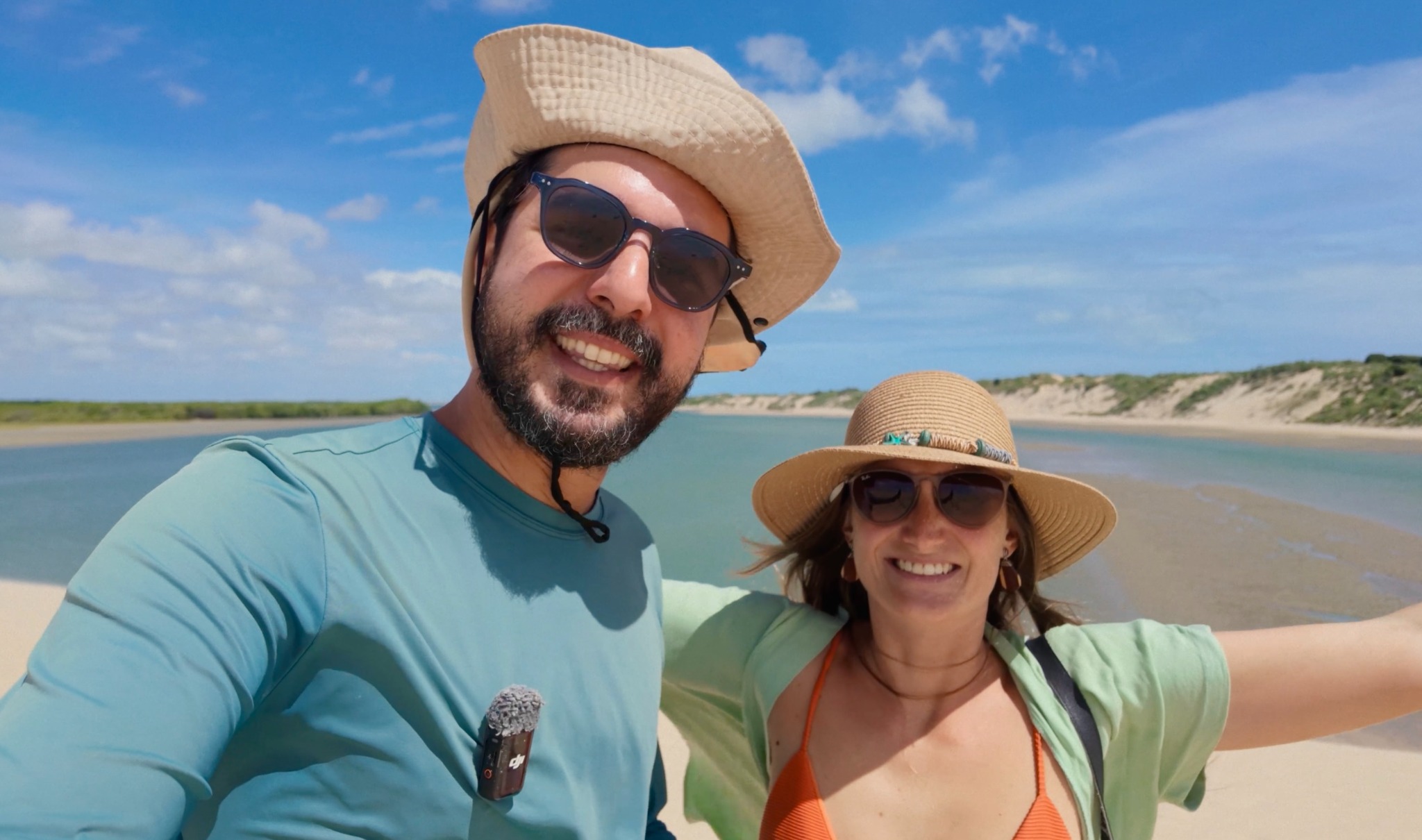 O casal de chapéu, diante de águas cristalinas