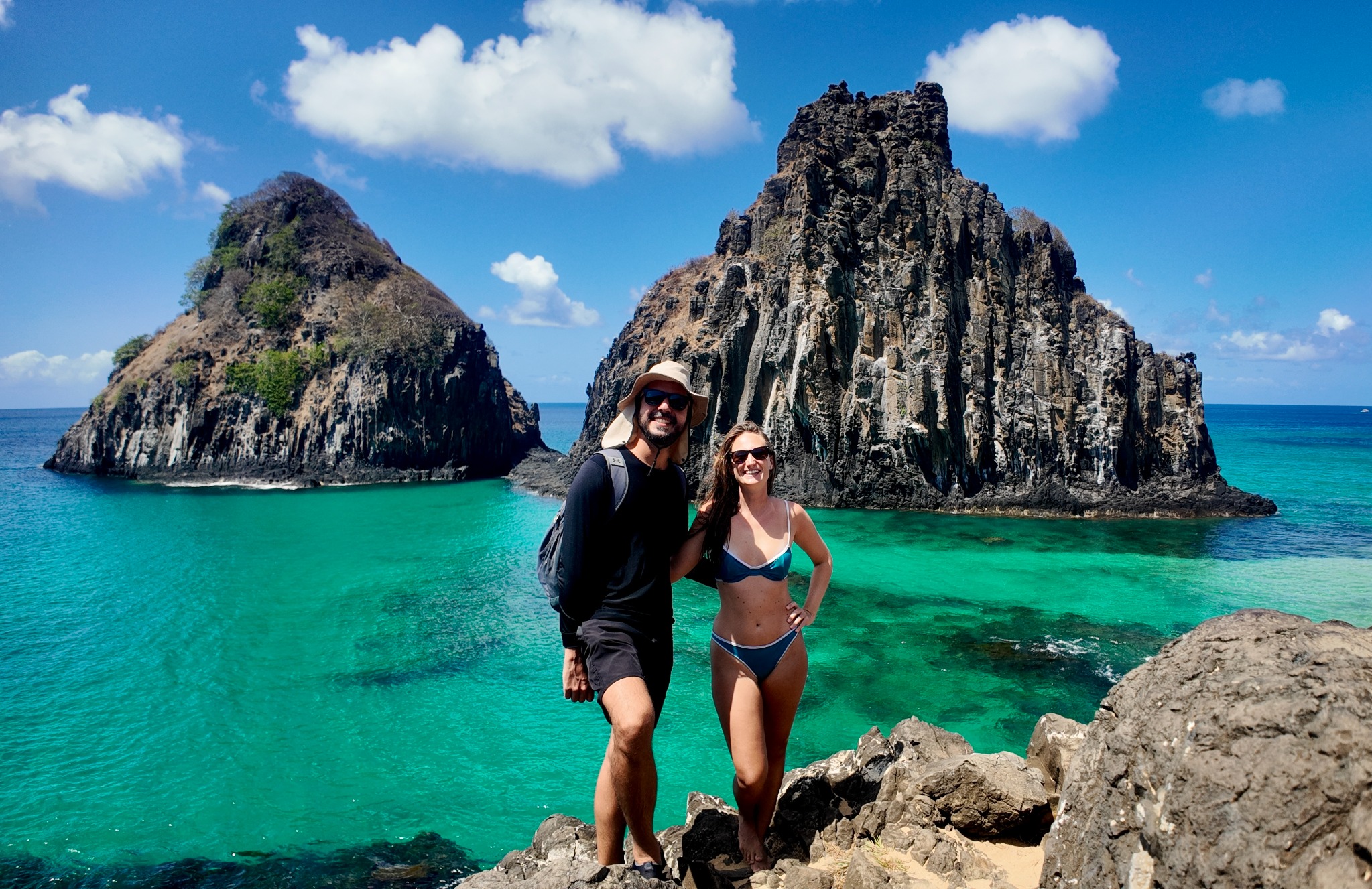 O casal diante das formações rochosas e do mar